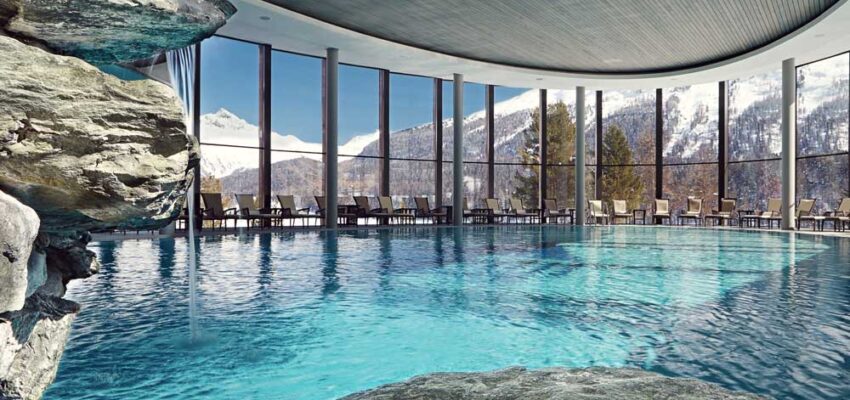 Piscine intérieure avec vue sur montagnes enneigées.