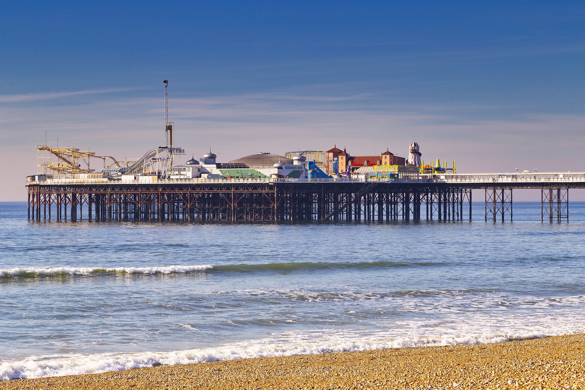 Brighton : jetée, mer calme, ciel dégagé, plage de galets.